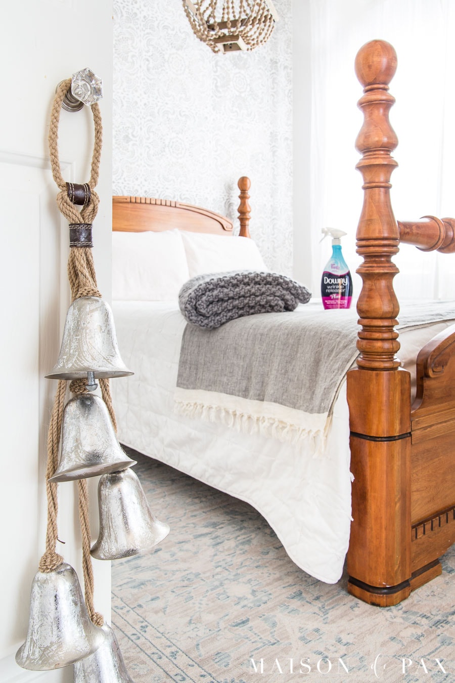 silver bells hanging on a closet door with an antique bed beyond