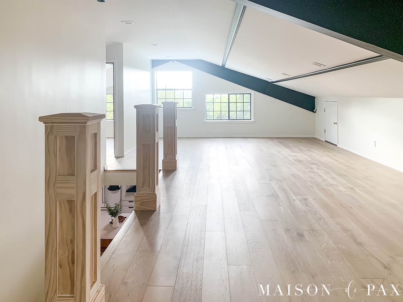 built out attic with windows, white oak floors, sloped ceilings, and black beams | Maison de Pax