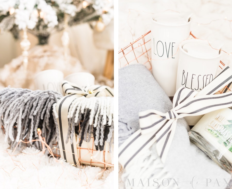 travel mugs that read "Love" and "Blessed", a fringed wool throw, and a holiday candle in a copper wire basket