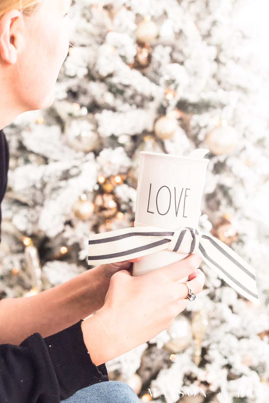 woman sitting in front of Christmas tree holding a mug that reads "love"