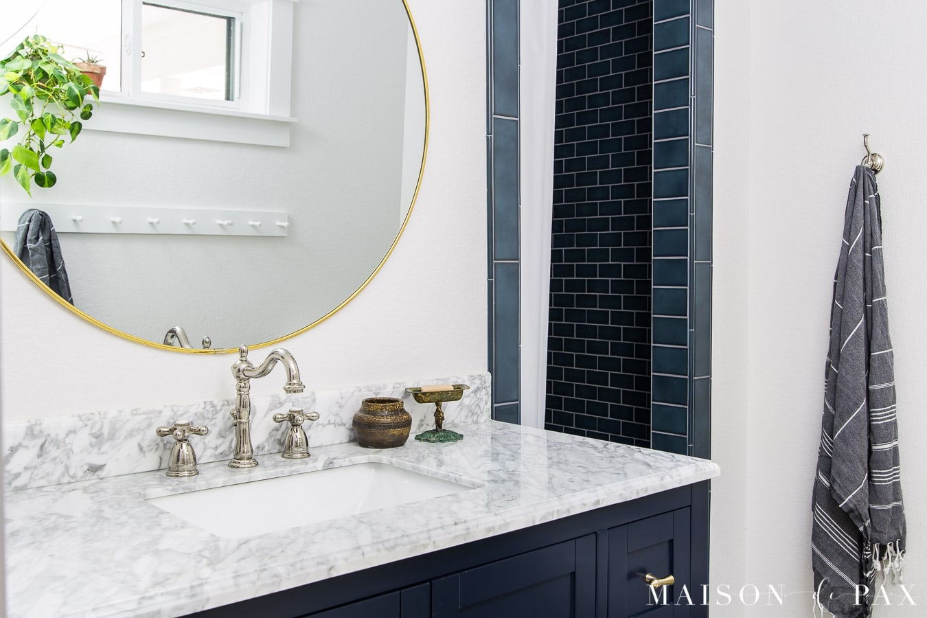round gold mirror over navy bathroom vanity