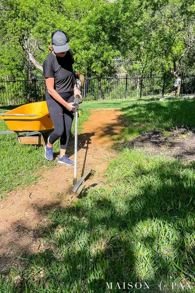 woman edging side of granite walkway with an edge trimmer