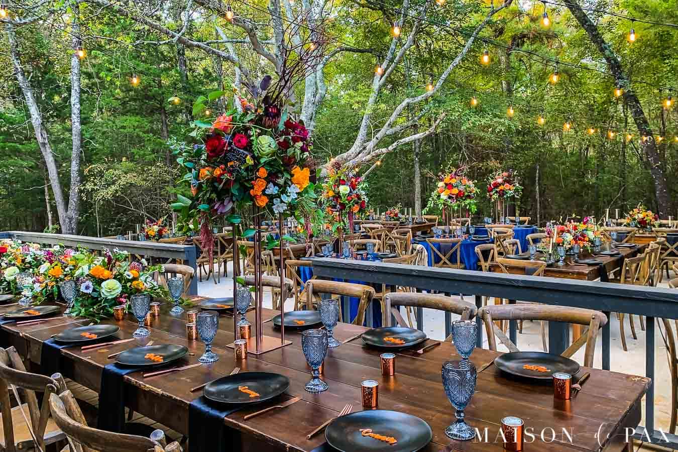 Create a rustic outdoor wedding table with candles, florals, string lights, and greenery - Maison de Pax
