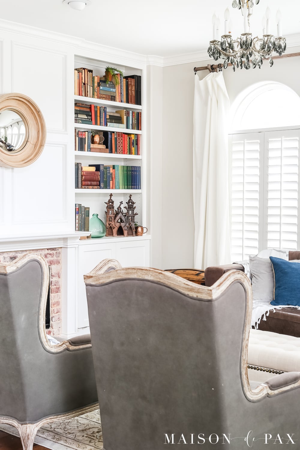 gray wingback chairs in front of a white fireplace and bookcase