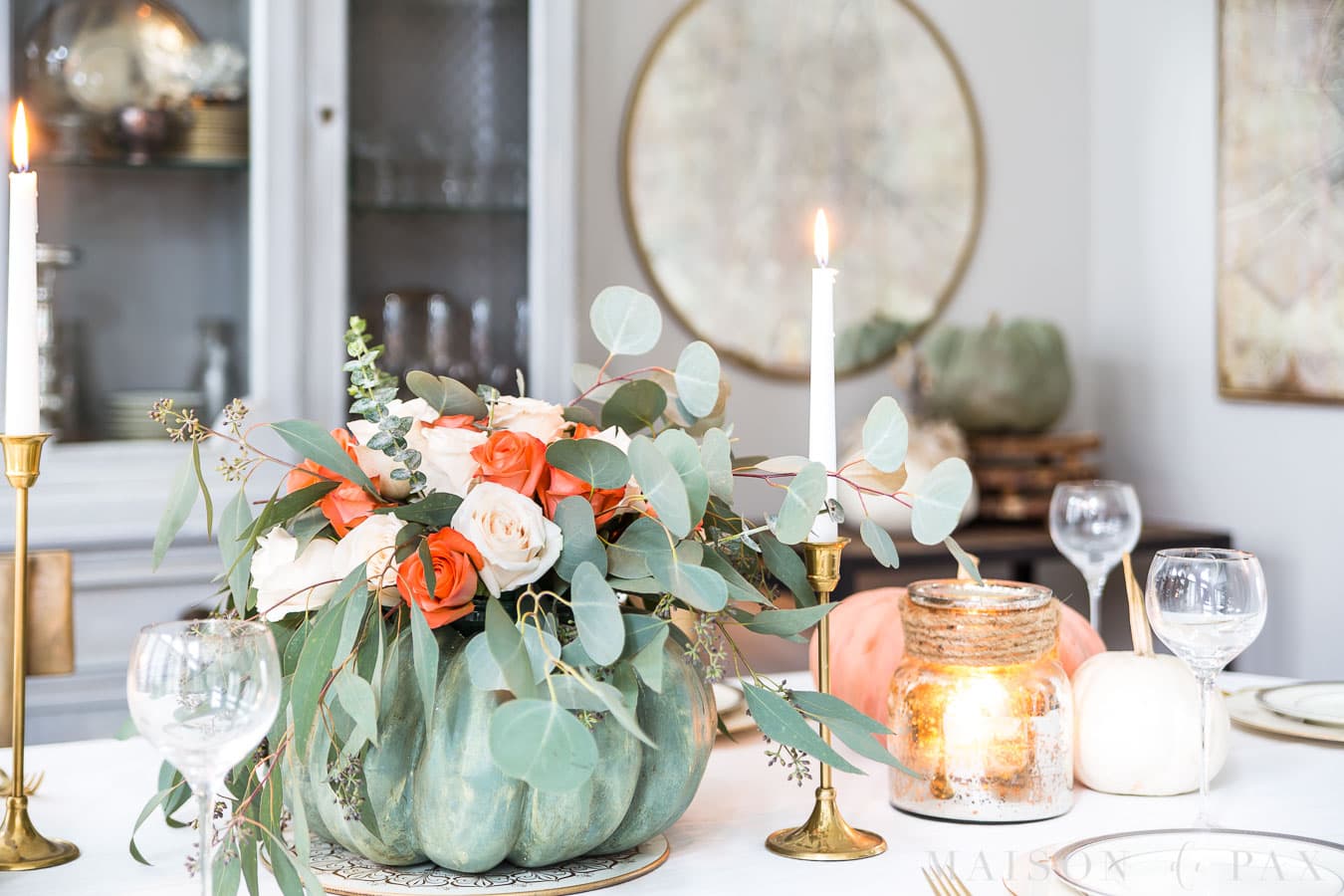 pumpkin with roses and eucalyptus, candles, and china creates an elegant Thanksgiving table.