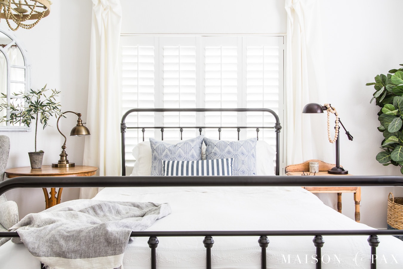 iron bed with white bedding and blue striped pillows- Maison de Pax