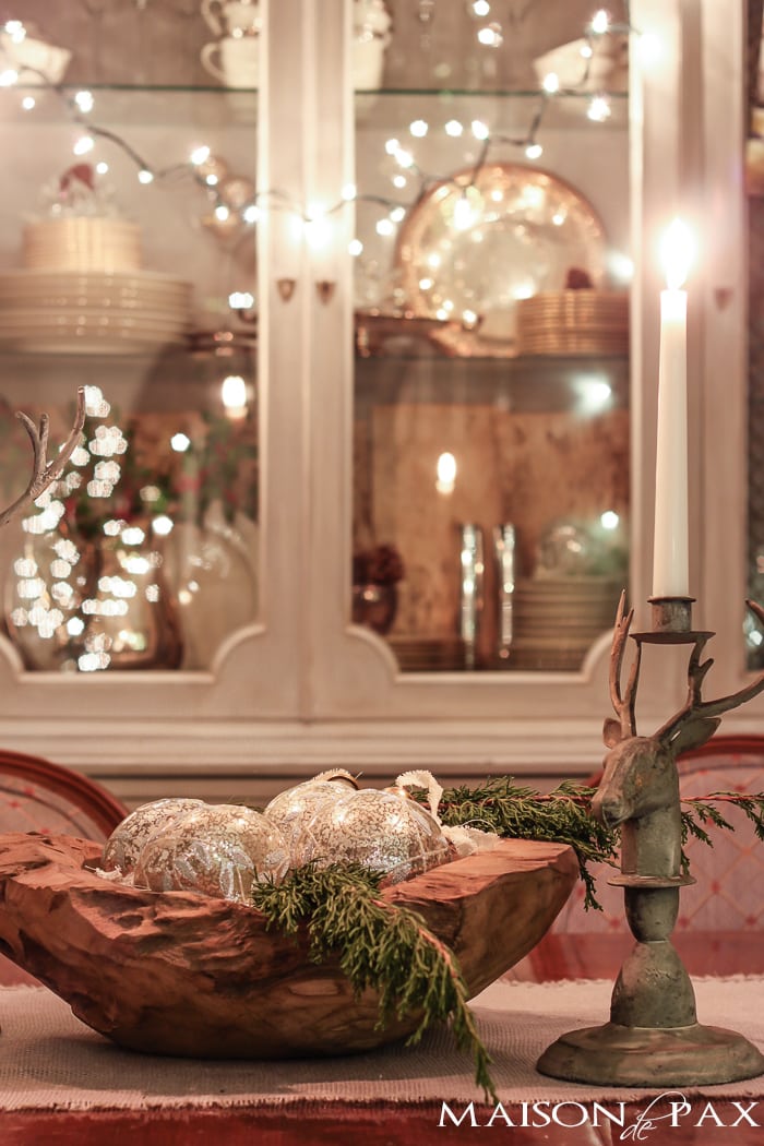 holiday decorating: Christmas table with reindeer candlesticks, string lights on china cabinet